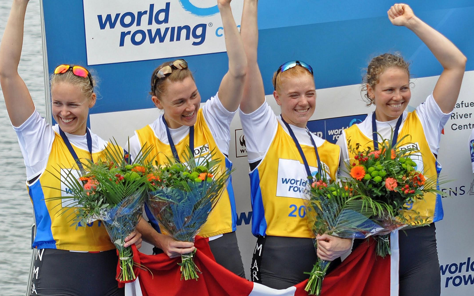 Fire kvindelige roere på medaljeskamlen med Dannebrog.